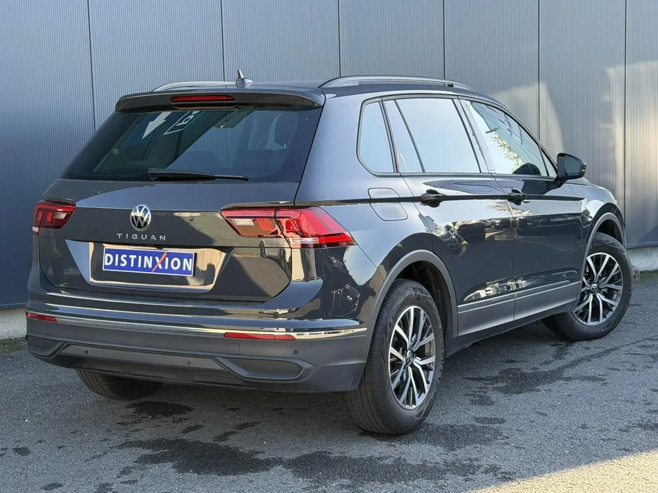 Volkswagen Tiguan 1.5 TSI gris Urano vu en 3/4 arrière droit avec jantes alliage 17 pouces et vitres surteintées.