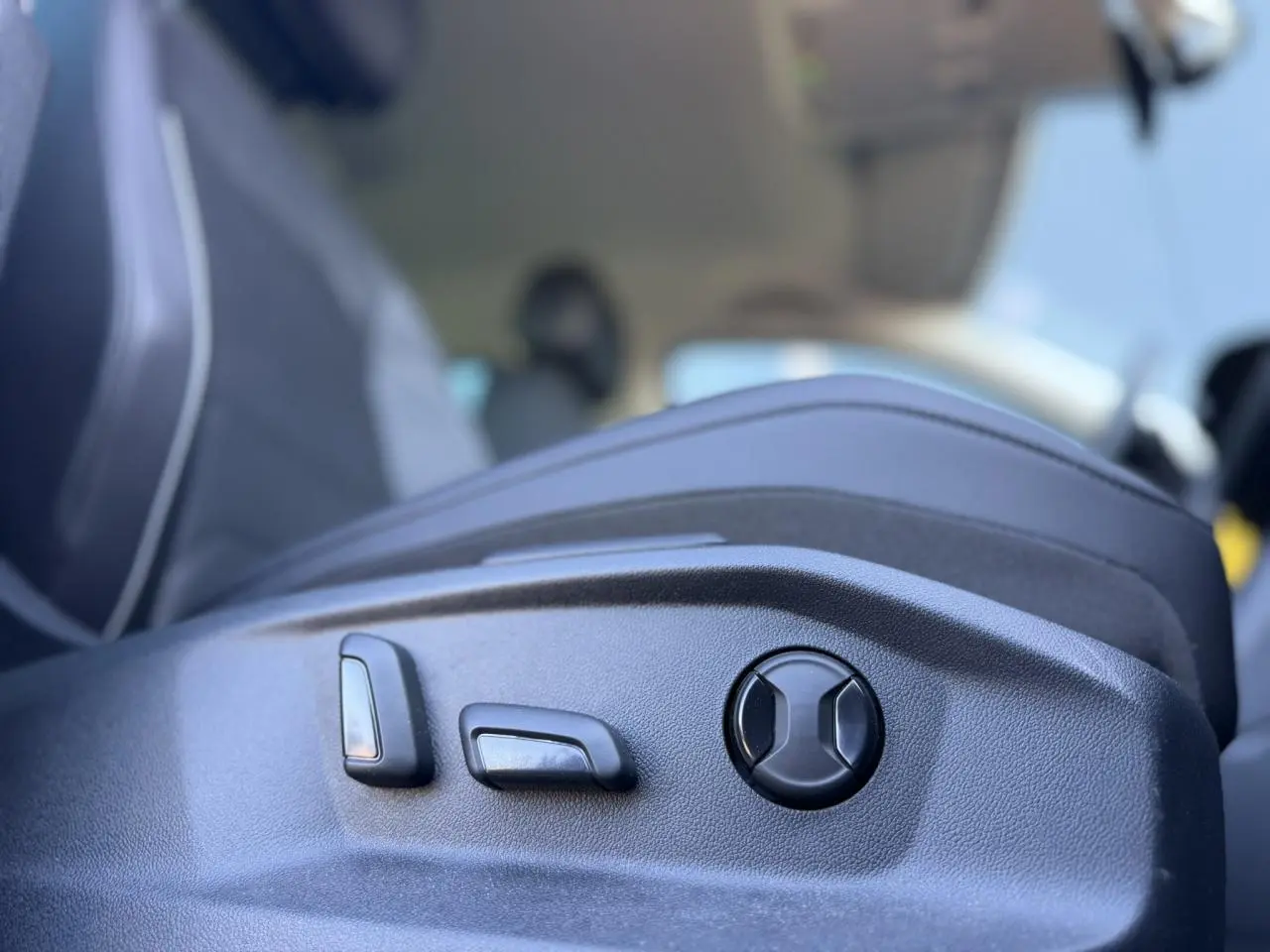 Gros plan sur les commandes de réglage électrique du siège avant côté gauche du Volkswagen Tiguan gris Urano 2024.
