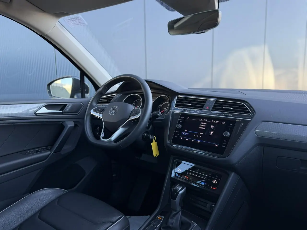 Vue intérieure côté conducteur du Volkswagen Tiguan 2024 avec tableau de bord noir et écran tactile central.