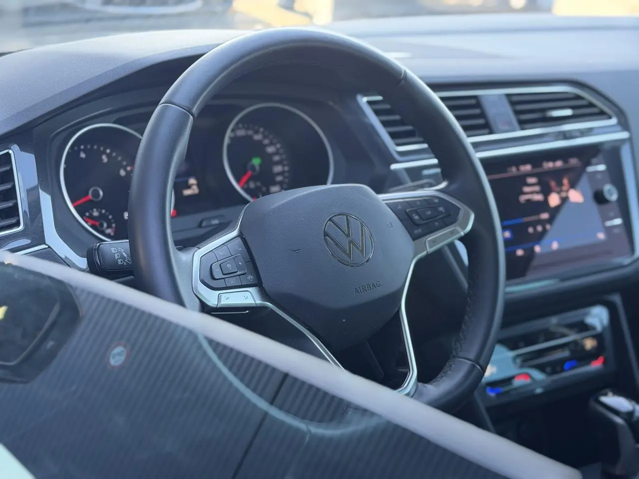 Vue rapprochée du volant cuir multifonctions et du tableau de bord noir du Volkswagen Tiguan 2024.