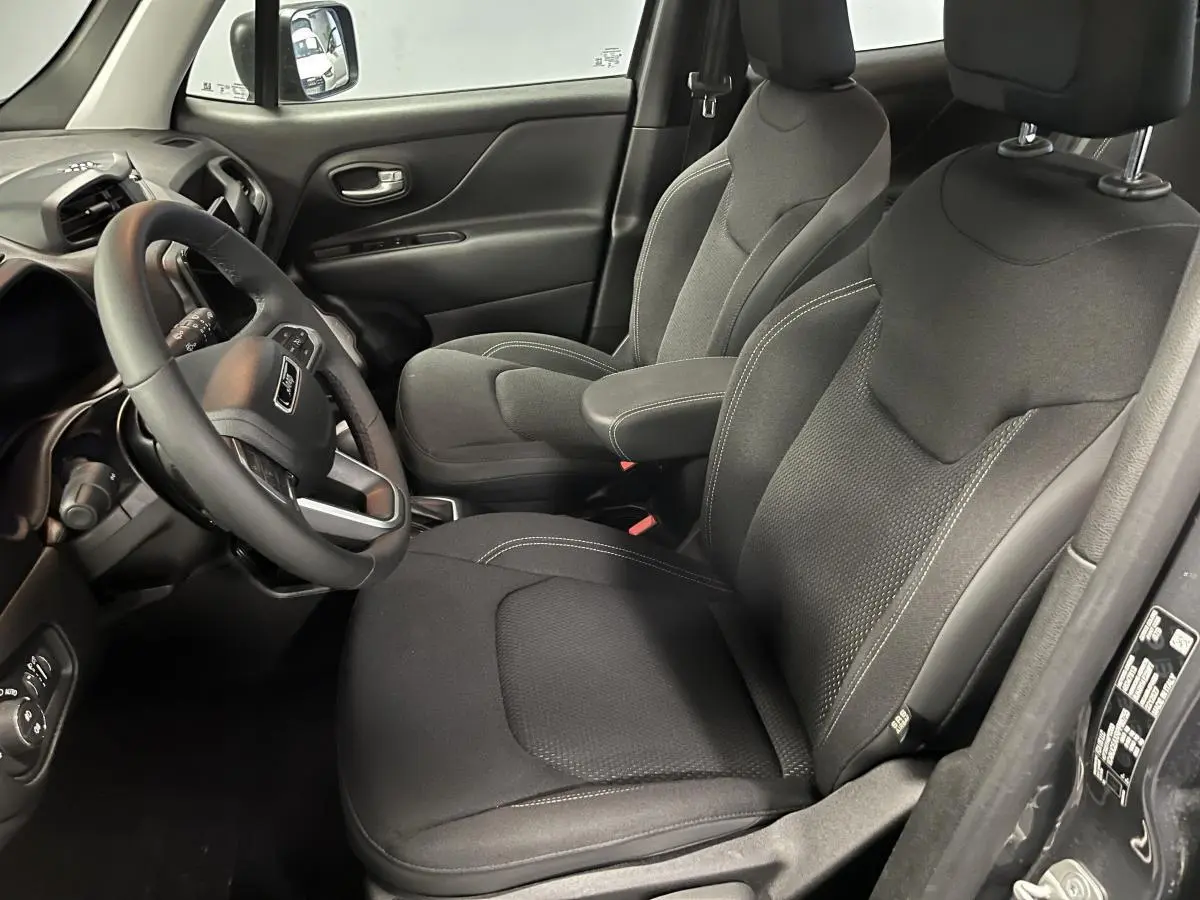 Intérieur du Jeep Renegade 2024, vue côté conducteur, sièges tissu noir avec surpiqûres grises et volant multifonction.