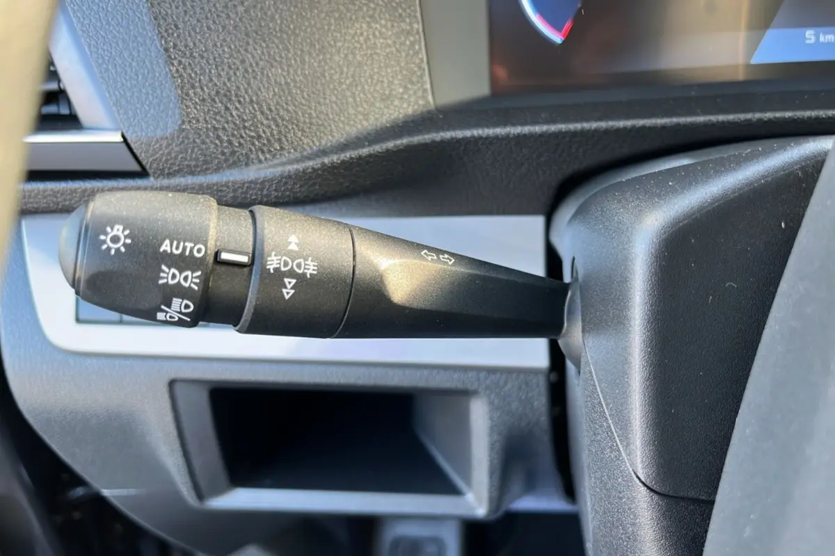 Gros plan sur la commande des feux et clignotants du Peugeot Traveller 2025 gris titane, côté gauche du volant.