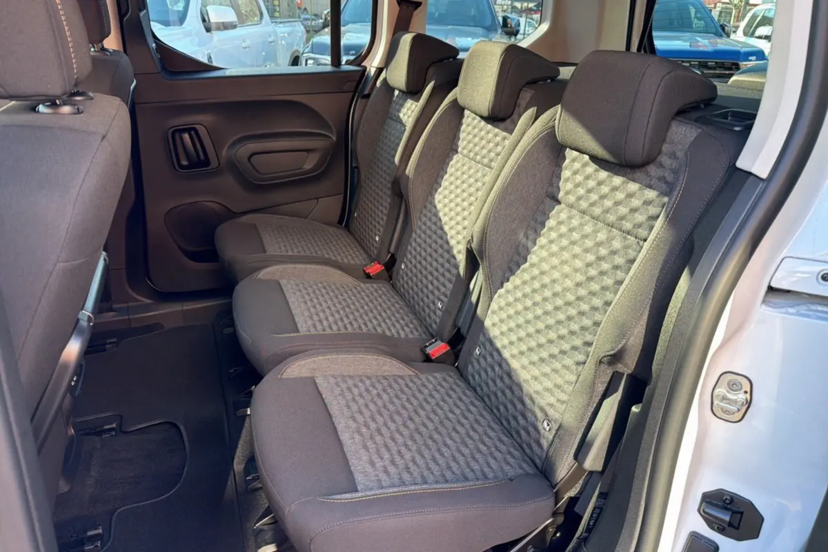 Vue latérale des sièges arrière en tissu gris du Peugeot Rifter blanc kaolin, porte arrière ouverte côté droit.