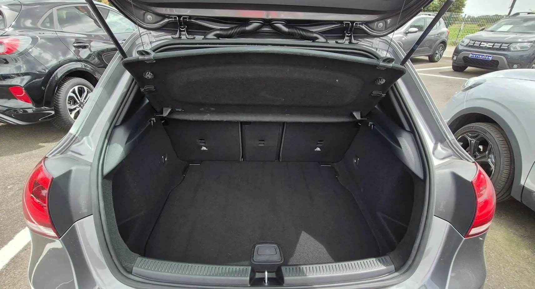 Coffre ouvert vu de l'arrière d'une Mercedes Classe A 180d gris foncé, montrant l'espace de chargement vide.