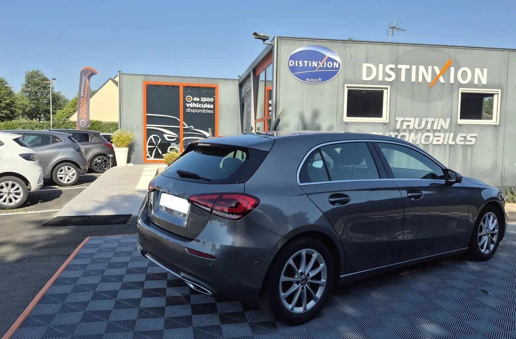 Vue 3/4 arrière droite d'une Mercedes Classe A 180d gris foncé, avec jantes alliage et feux arrière LED visibles.