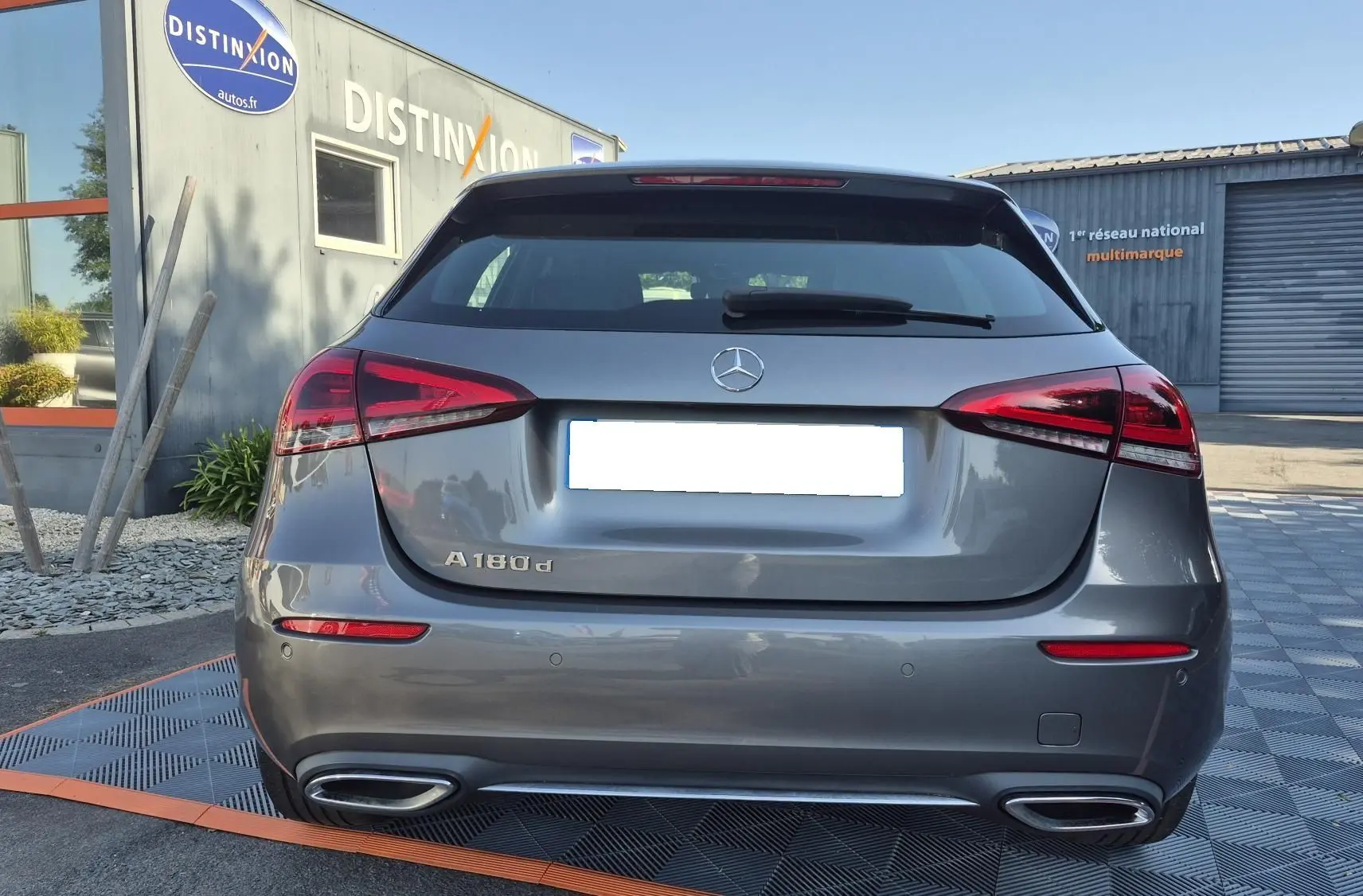 Vue arrière d'une Mercedes Classe A 180d gris foncé, avec feux LED et double sortie d'échappement chromée visible.