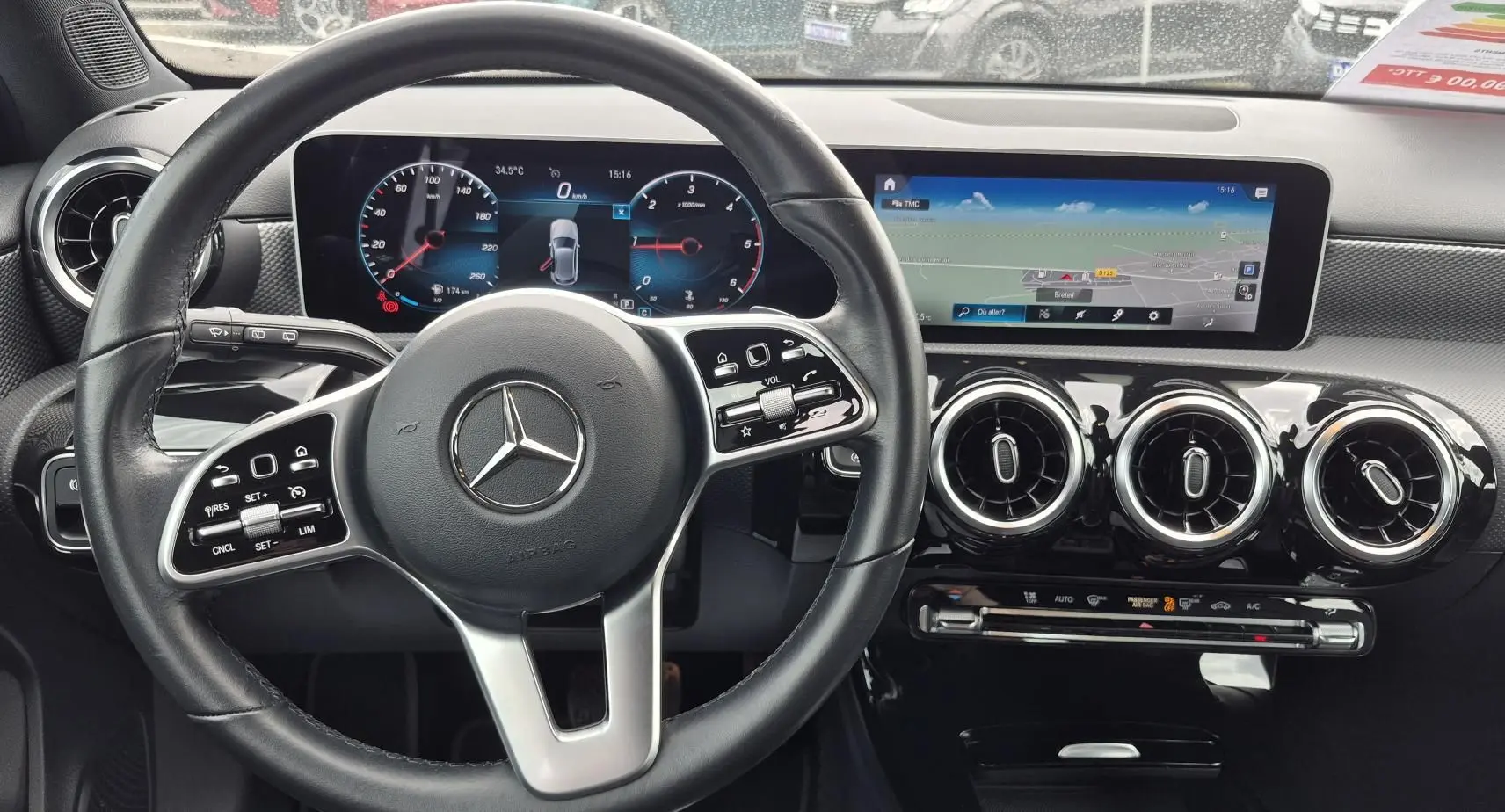 Vue intérieure centrée sur le volant cuir noir et le tableau de bord numérique avec écran tactile du Mercedes Classe A 180d gris foncé.
