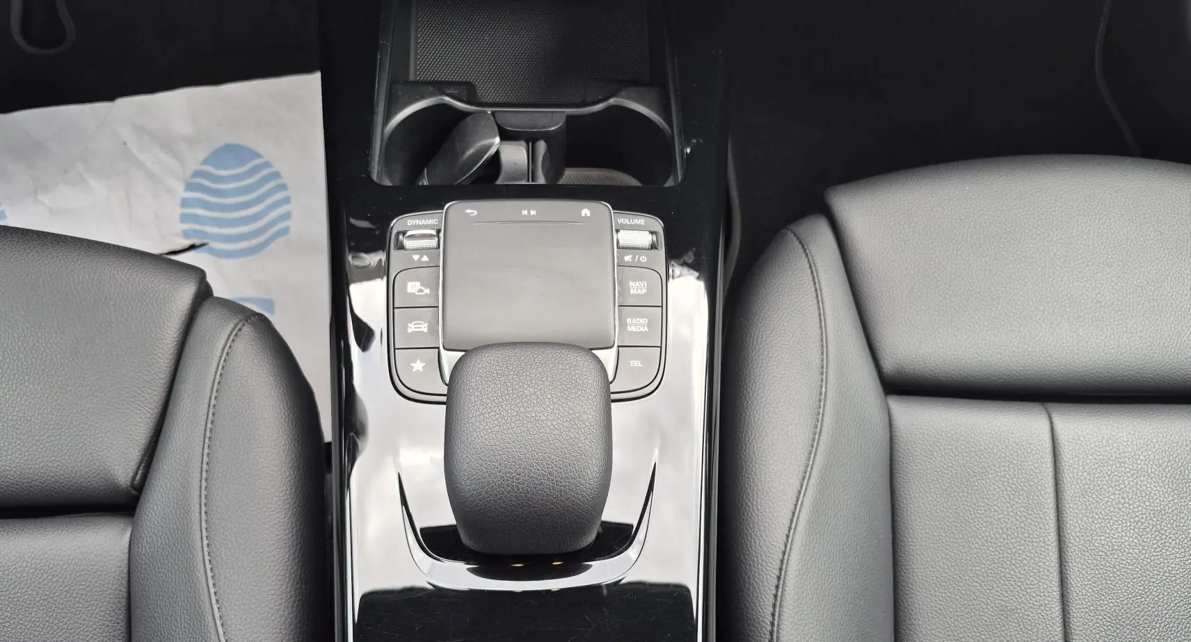 Gros plan sur la console centrale noire brillante et le levier de vitesse cuir noir de la Mercedes Classe A 180d 2020.