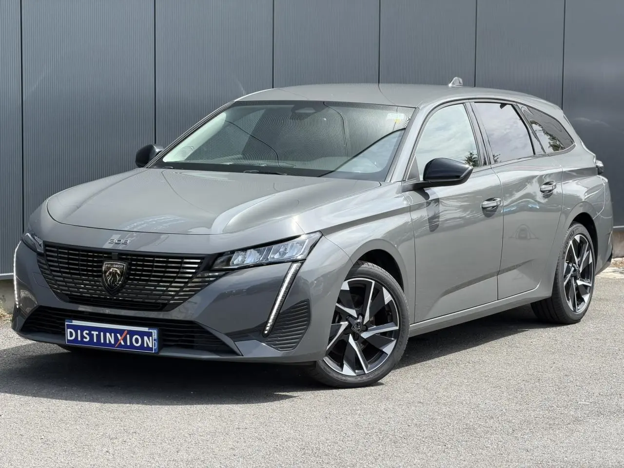Peugeot 308 SW gris Selenium vue 3/4 avant droit, jantes alliage 17'' et calandre noire distinctive.