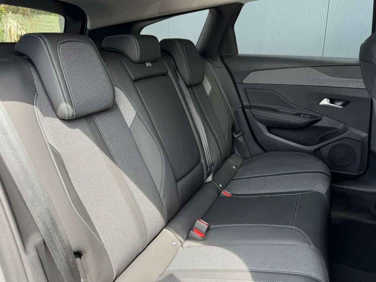 Vue latérale droite des sièges arrière en sellerie tri matières noire et grise de la Peugeot 308 SW 2025.