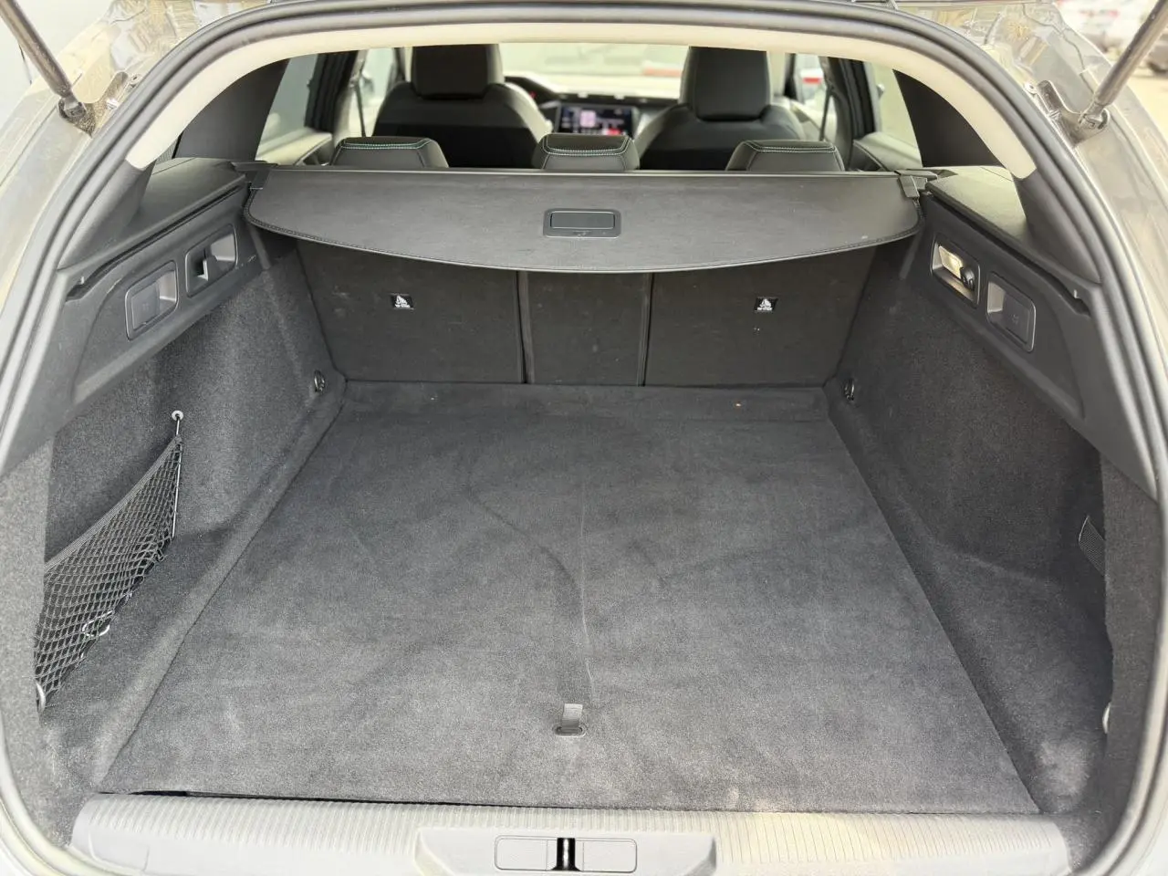 Coffre spacieux de Peugeot 308 SW gris Selenium vu de l'arrière avec cache-bagages et banquette rabattue partiellement visible.
