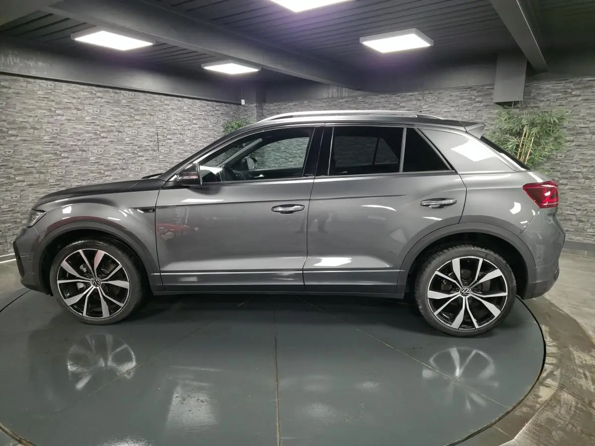 Vue de profil côté gauche d'un Volkswagen T-Roc gris métallisé avec jantes alliage 19 pouces et finitions R-Line.