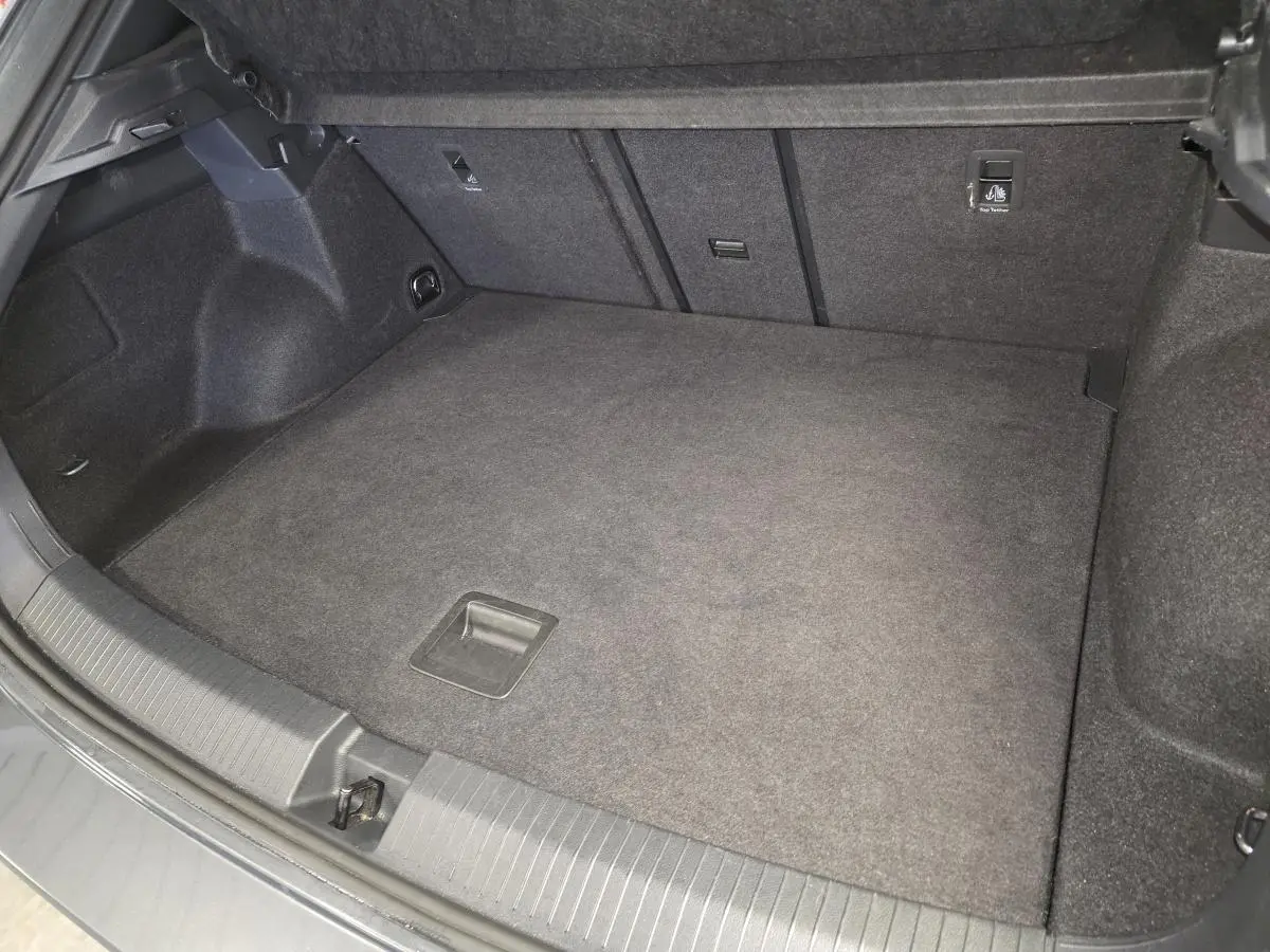 Coffre spacieux vu de face, intérieur gris foncé, plancher plat et habillage tissu dans un Volkswagen T-Roc 2025.