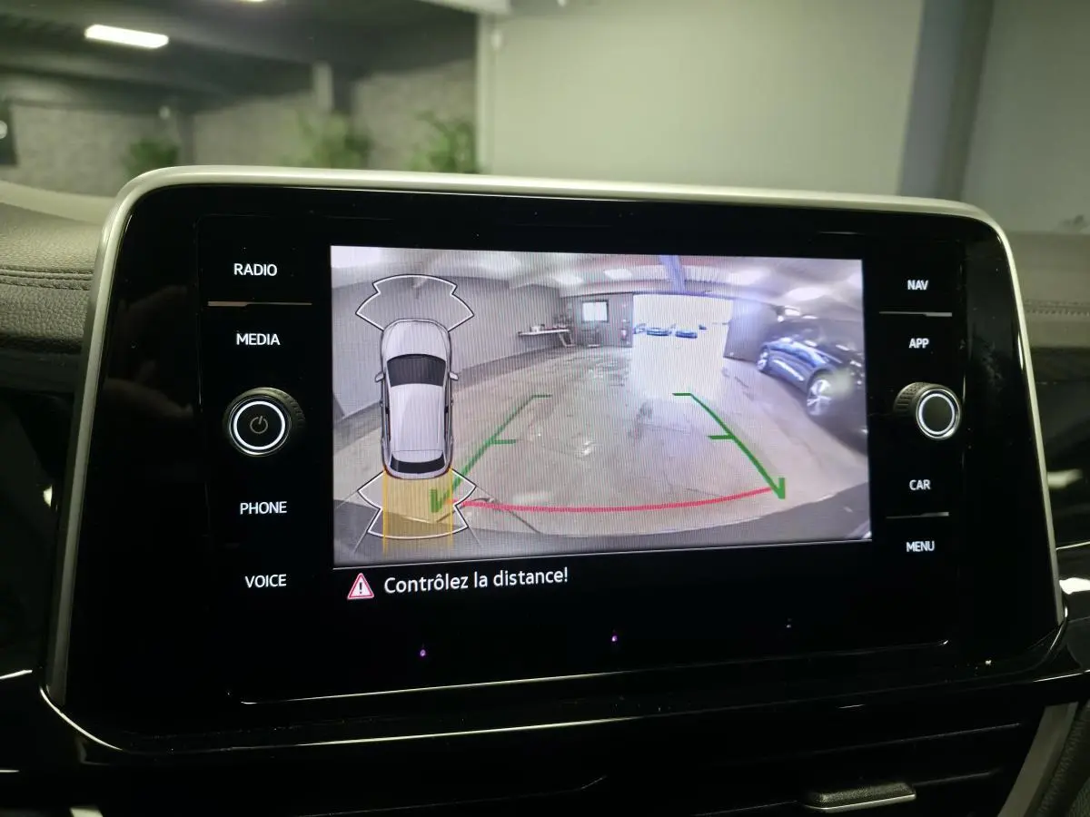 Écran tactile affichant la caméra de recul du Volkswagen T-Roc gris avec repères de stationnement en garage.