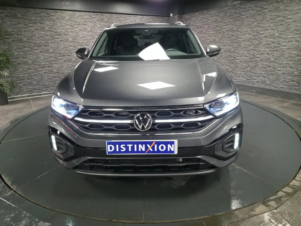 Vue avant d'un Volkswagen T-Roc gris métallisé 2025 avec calandre R-Line et phares Matrix LED allumés.