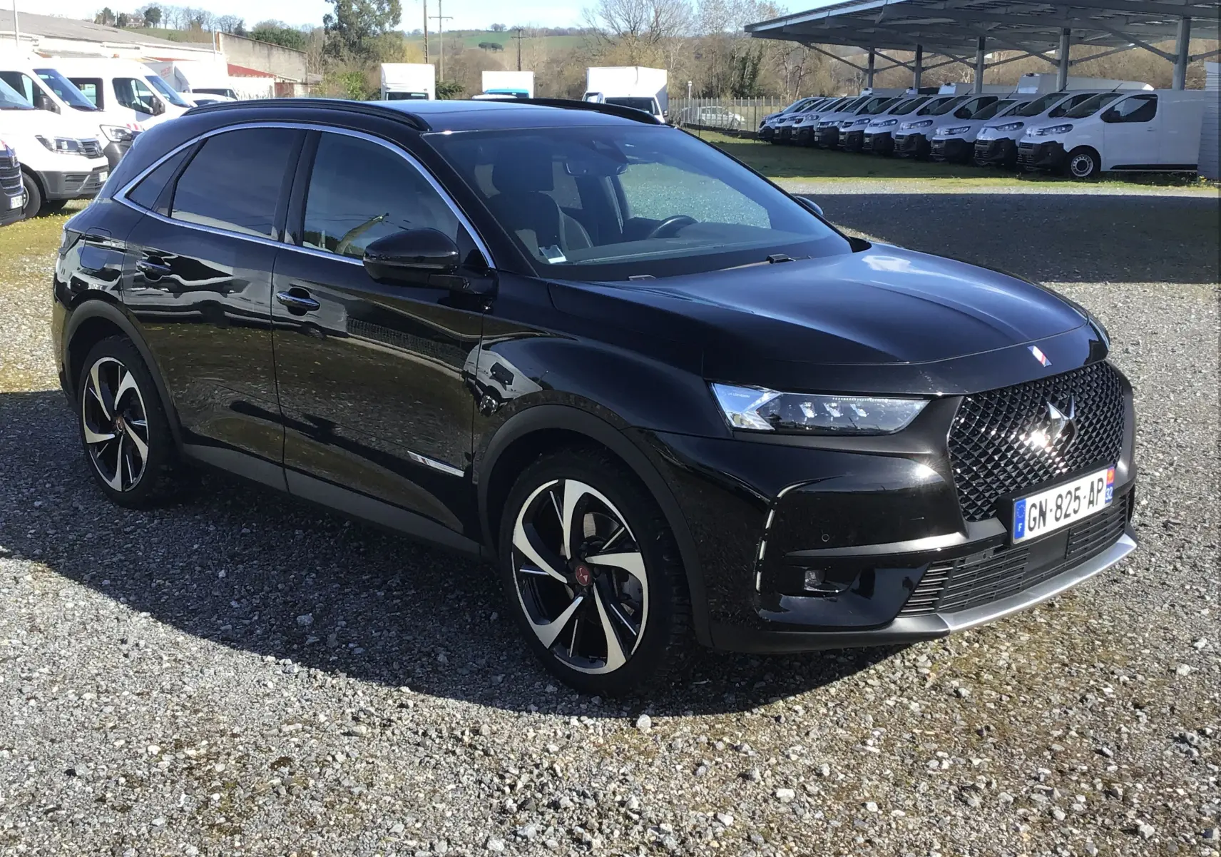 DS7 Crossback noir en 3/4 avant droit, mettant en valeur sa calandre distinctive et ses jantes bicolores élégantes.