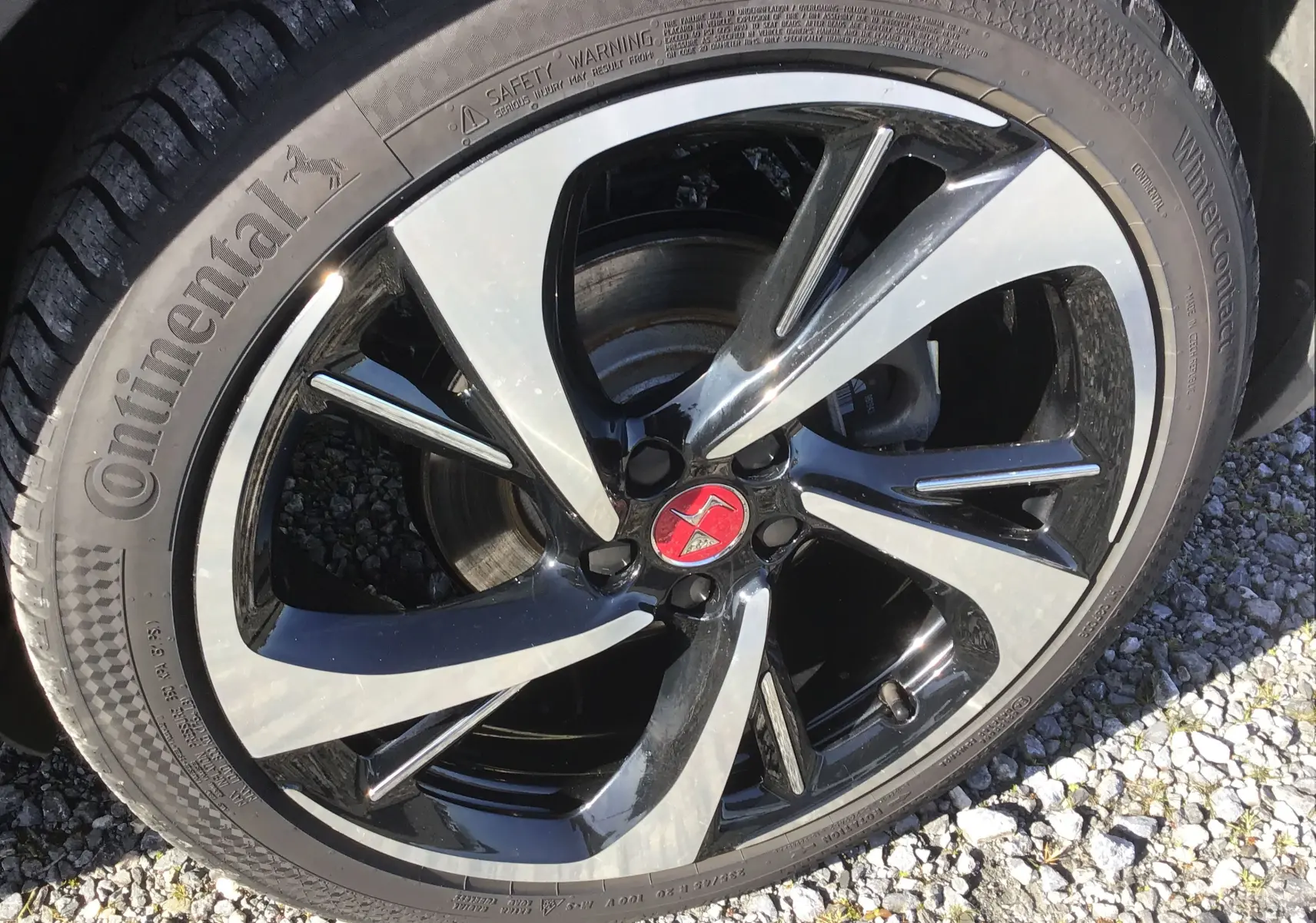 Gros plan sur la jante noire et argentée du DS7 Crossback 2023, avec logo DS rouge au centre et pneu Continental hiver.