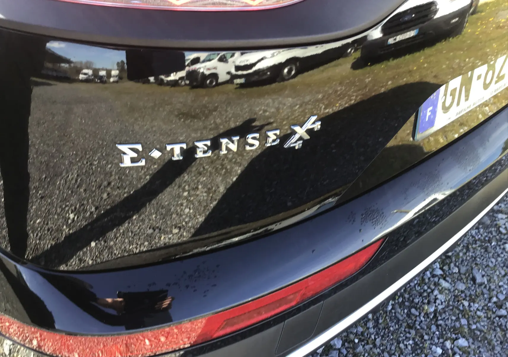 Gros plan sur l'arrière noir brillant du DS7 Crossback E-TENSE 4x4 avec logo distinctif et partie du pare-chocs visible.