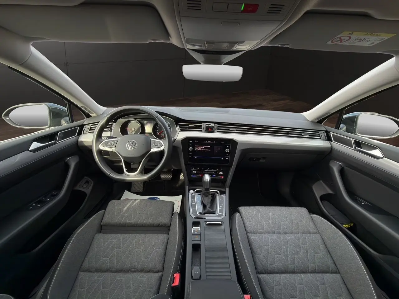 Vue intérieure avant de la Volkswagen Passat SW 2022, tableau de bord moderne et sièges tissu gris noir.