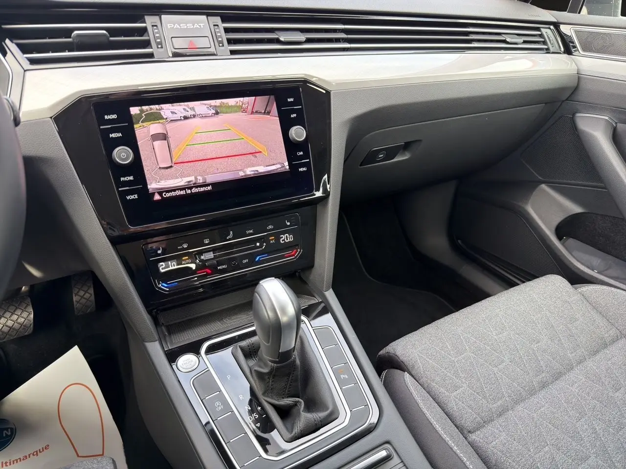 Vue intérieure centrée sur la console centrale et l’écran tactile affichant la caméra de recul de la Volkswagen Passat SW gris manganèse.