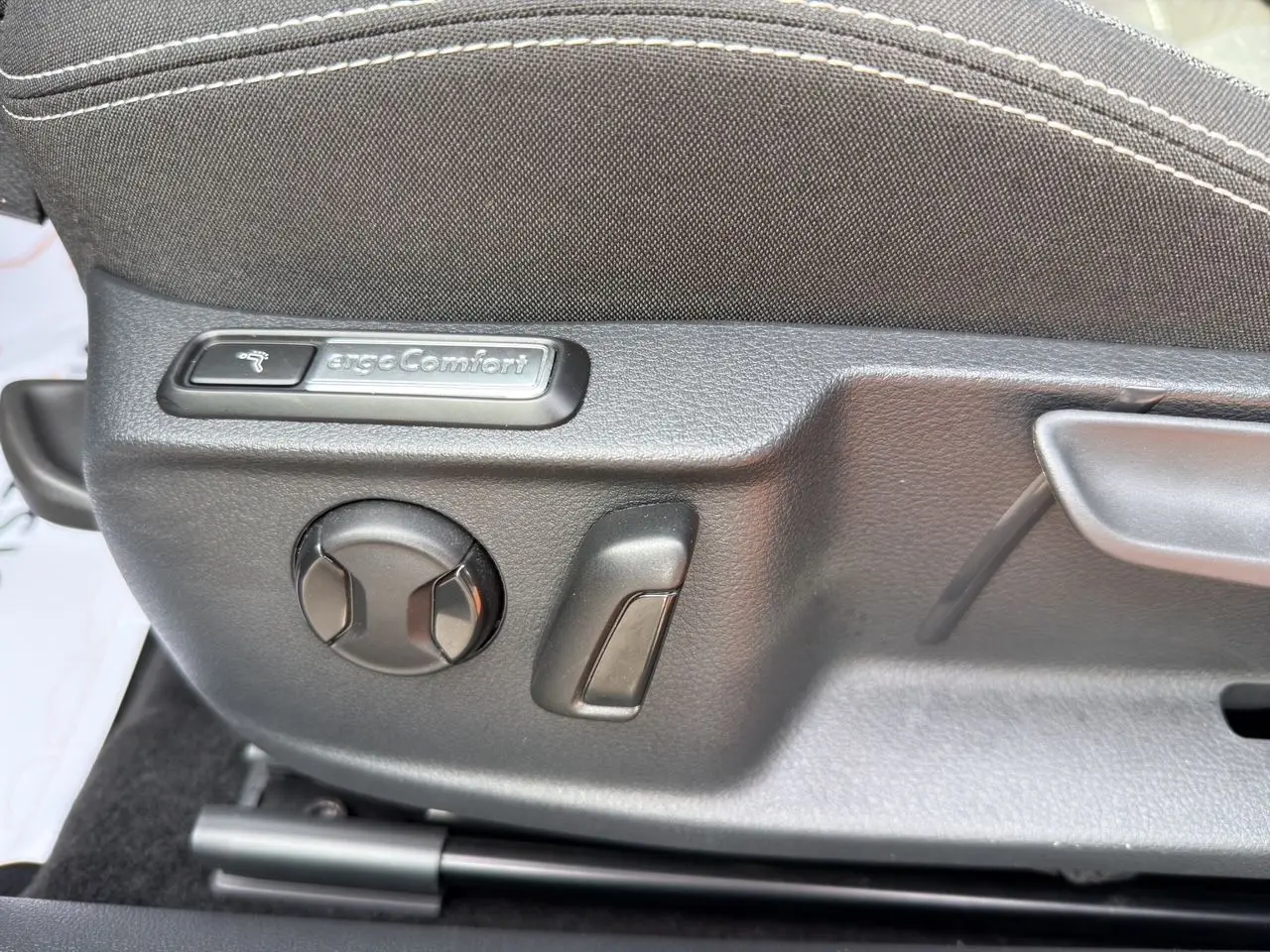 Gros plan sur les commandes de réglage siège tissu gris noir de la Volkswagen Passat SW 2.0 TDI Business.