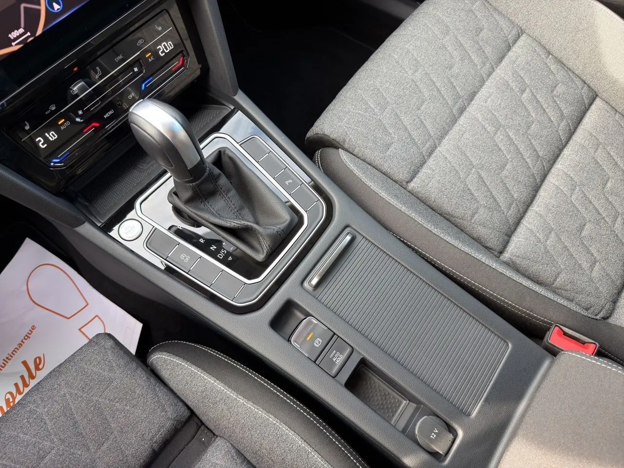Vue rapprochée de la console centrale et levier de vitesse automatique d’une Volkswagen Passat SW 2.0 TDI, sièges tissu gris.
