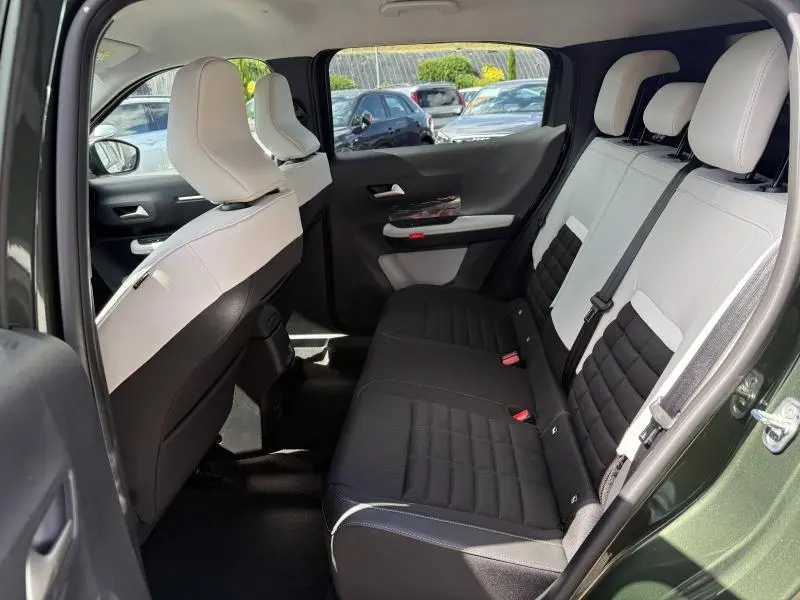 Vue intérieure arrière droite du Citroën C3 Aircross 2026 vert Montana avec sièges bicolores noir et blanc.