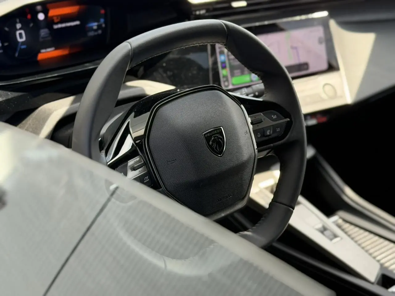 Gros plan sur le volant cuir noir et le tableau de bord numérique du Peugeot 308 SW 2025, intérieur moderne et épuré.