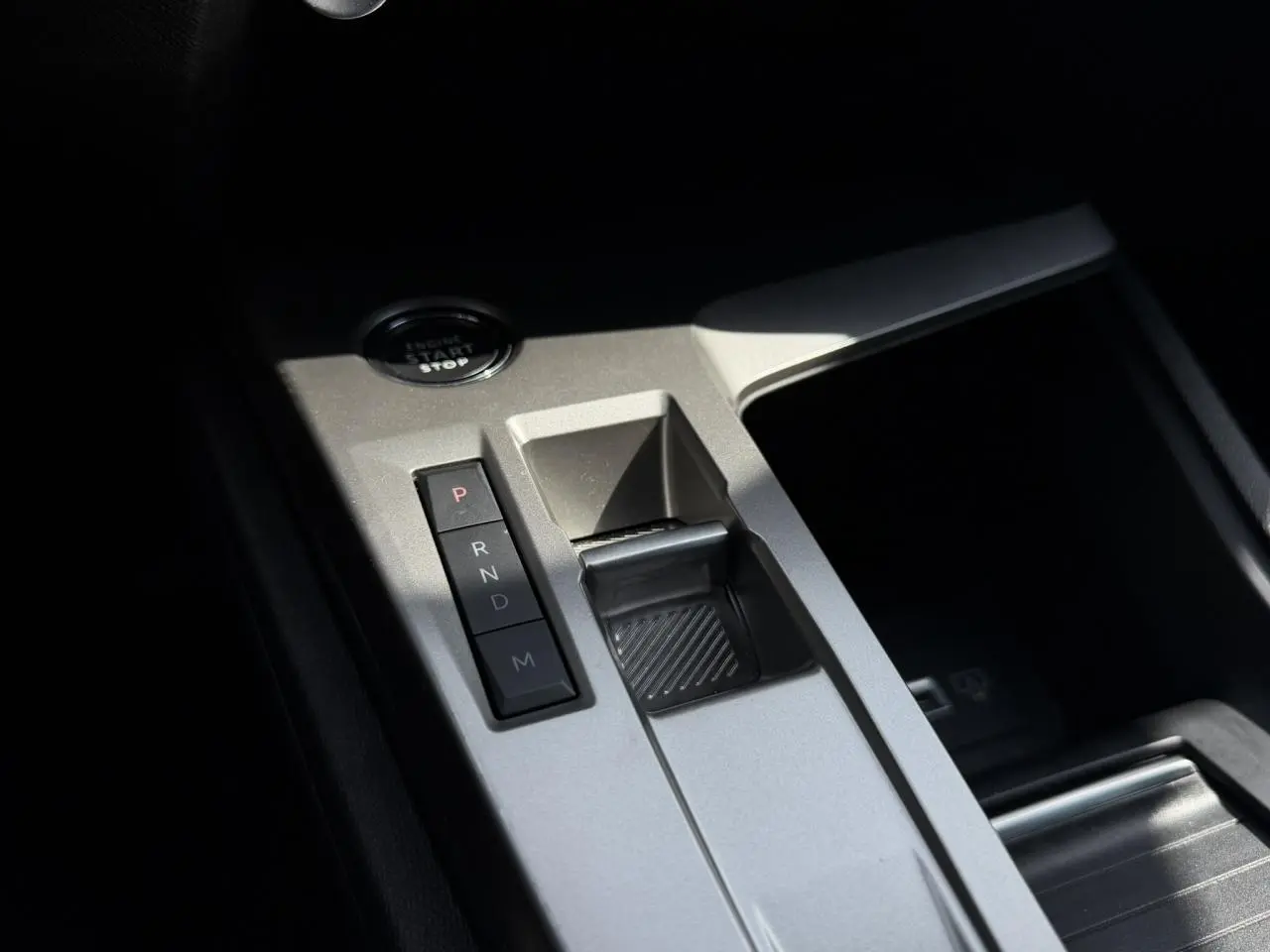 Gros plan sur la console centrale grise du Peugeot 308 SW 2025 avec sélecteur de boîte auto et bouton start/stop.