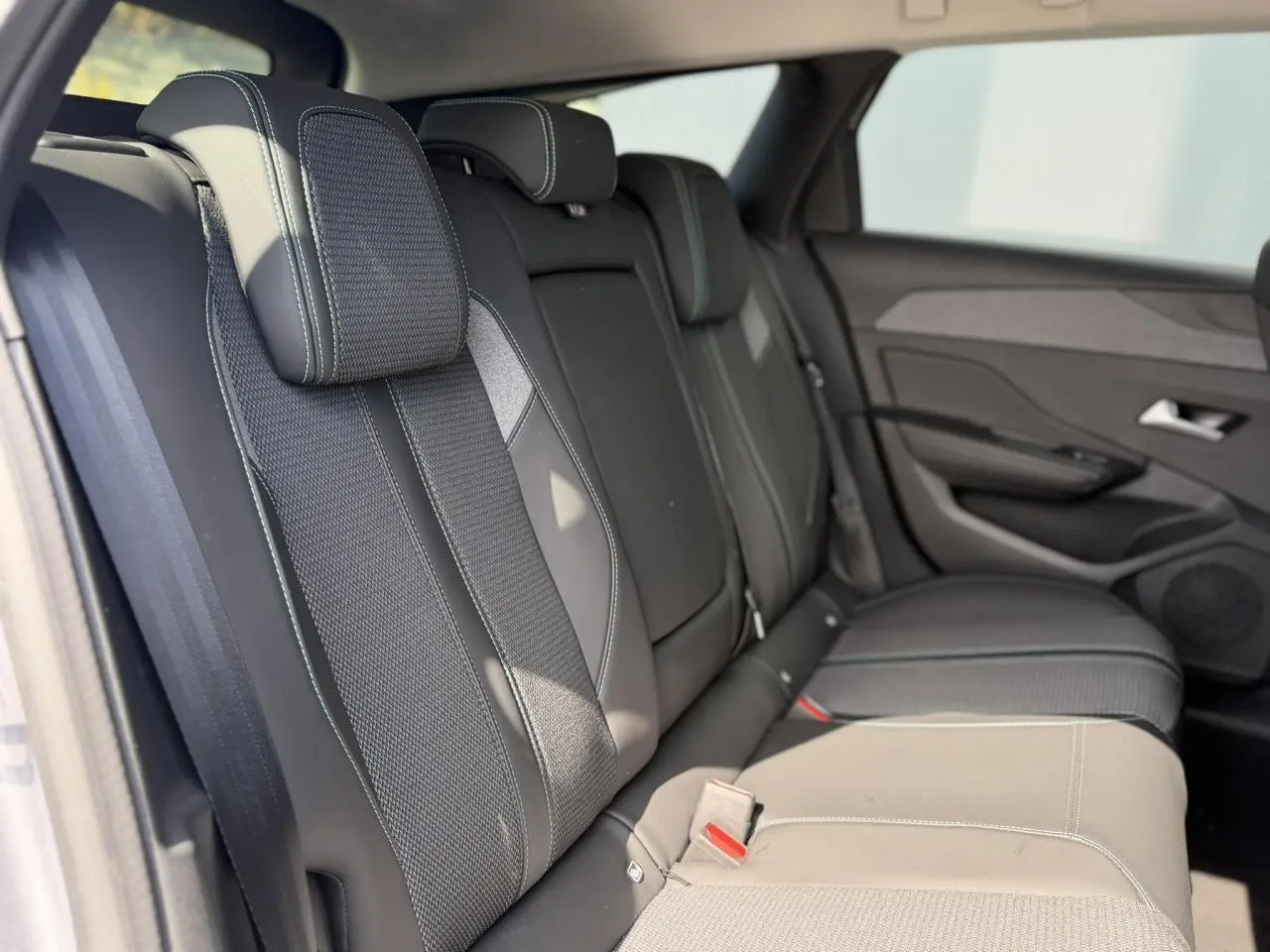 Vue latérale droite des sièges arrière en sellerie tri matières gris foncé avec surpiqûres bleues du Peugeot 308 SW 2025.
