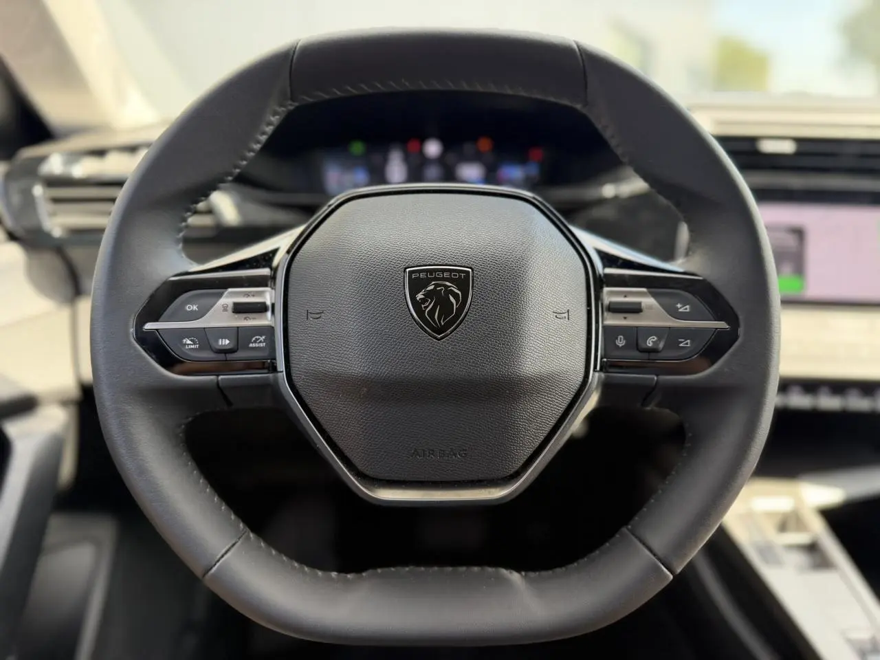 Gros plan sur le volant cuir noir du Peugeot 308 SW 2025 avec commandes intégrées et logo lion central.