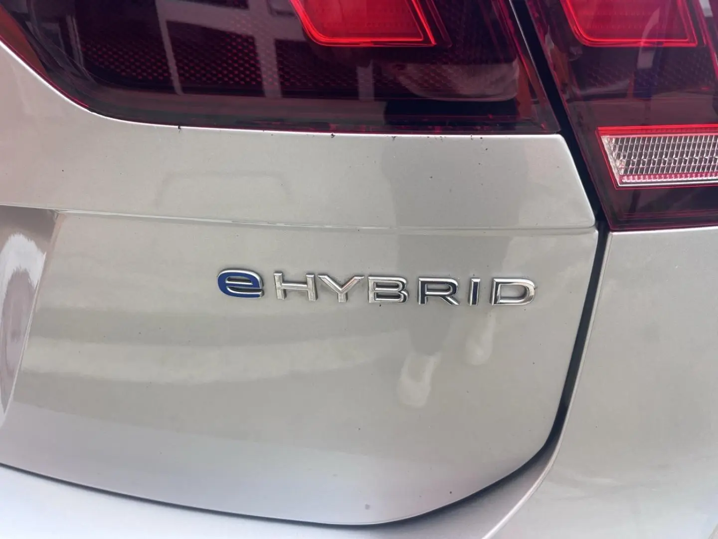 Gros plan sur le logo eHybrid à l'arrière droite d'un Volkswagen Tiguan gris dauphin métallisé.