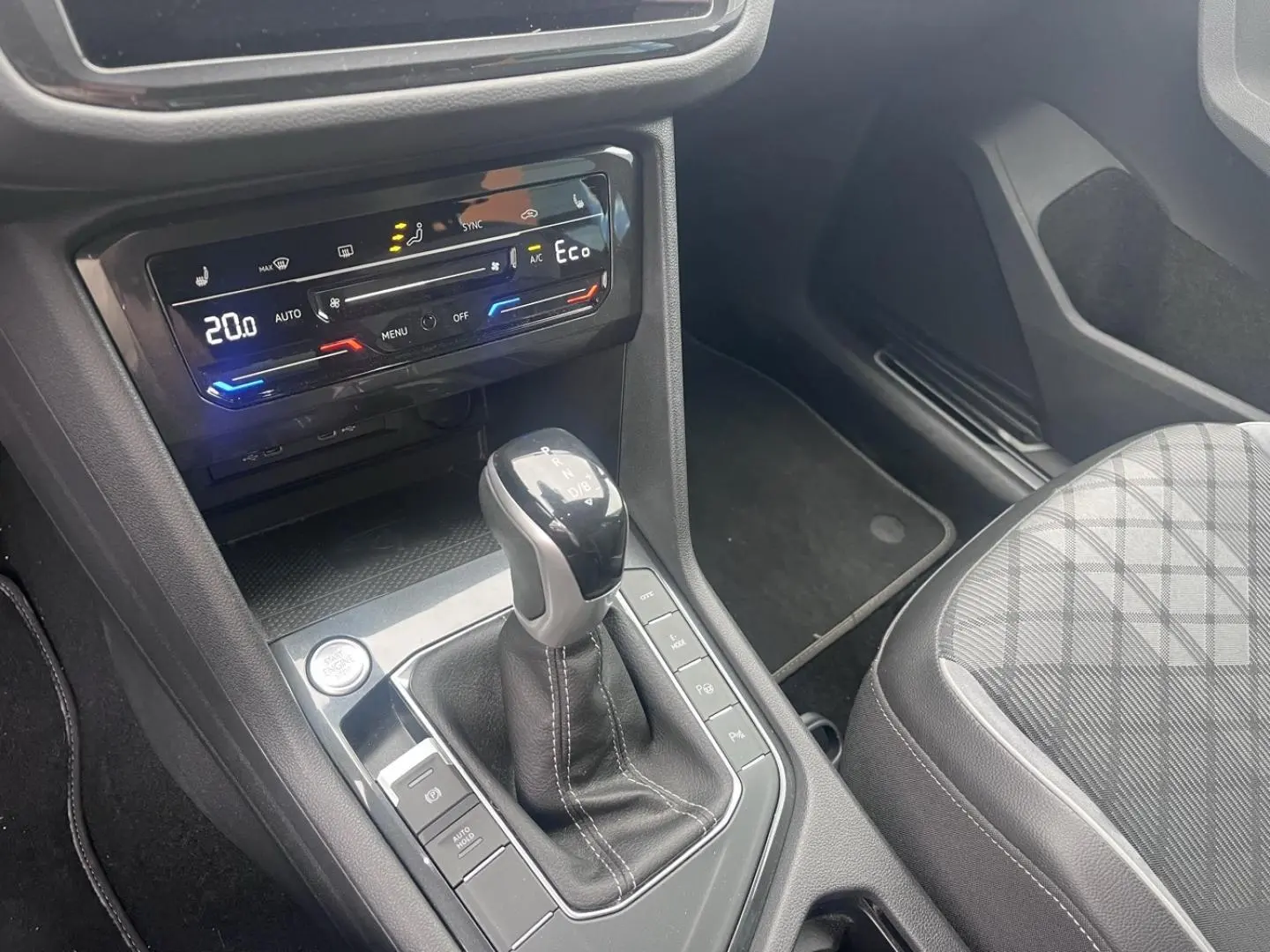 Vue intérieure centrée sur la console centrale du Volkswagen Tiguan gris Dauphin avec levier de vitesse et commandes climatiques.