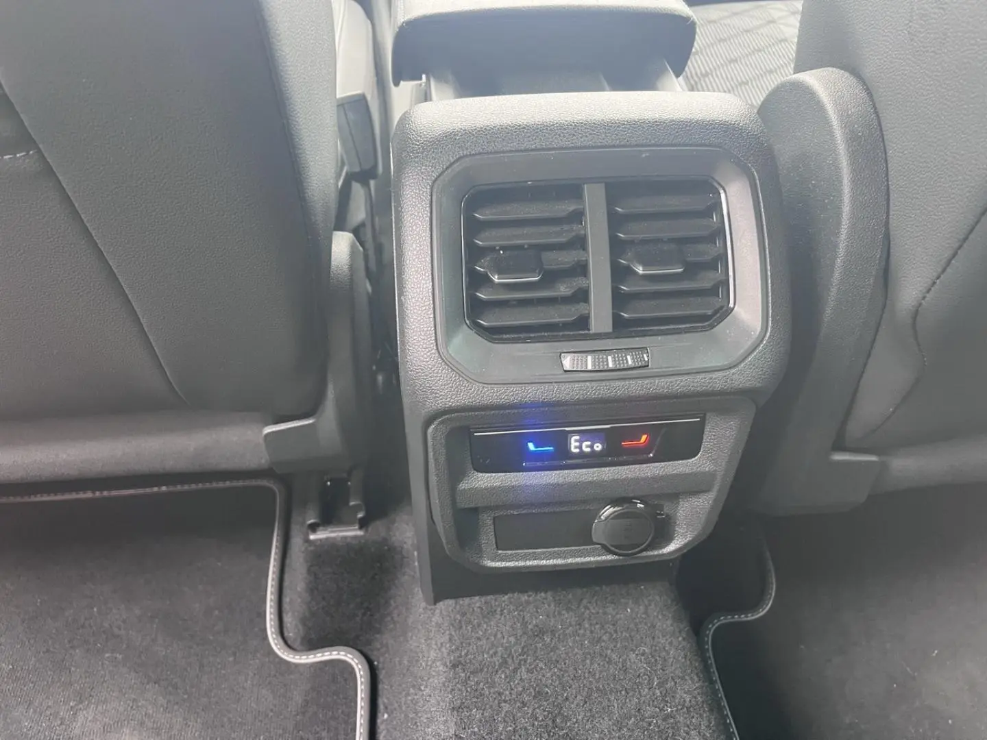 Vue rapprochée de la console arrière du Volkswagen Tiguan gris Dauphin avec commandes climatisation et prise 12V.