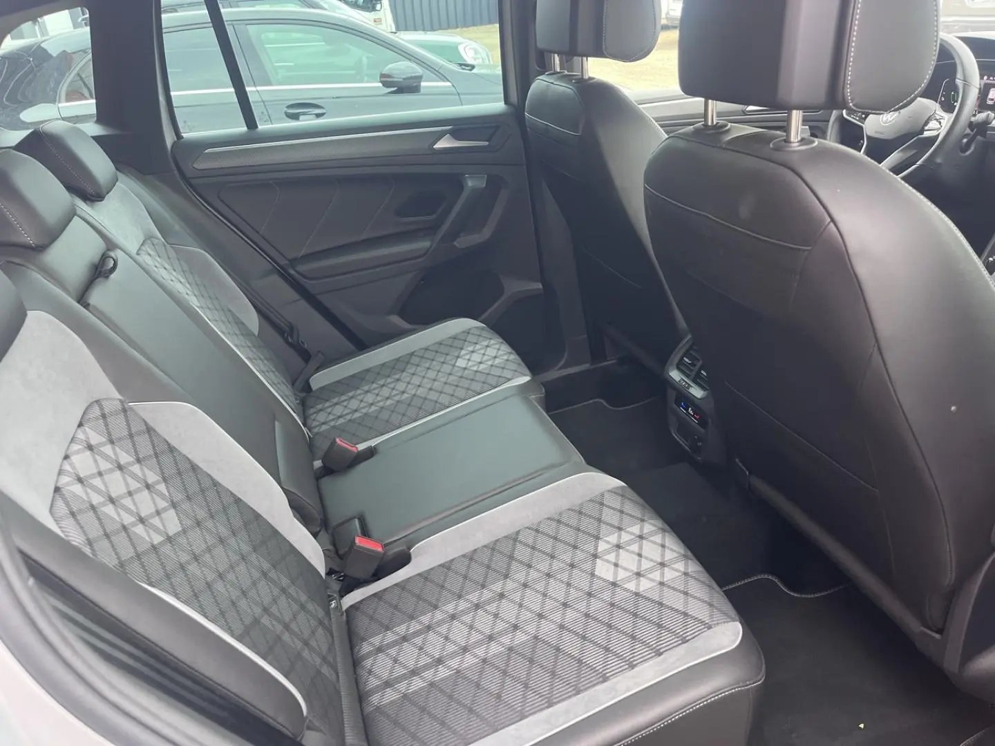 Vue intérieure arrière du Volkswagen Tiguan 1.4 eHybrid 2023, sièges arrière en tissu et cuir noir avec motifs géométriques.