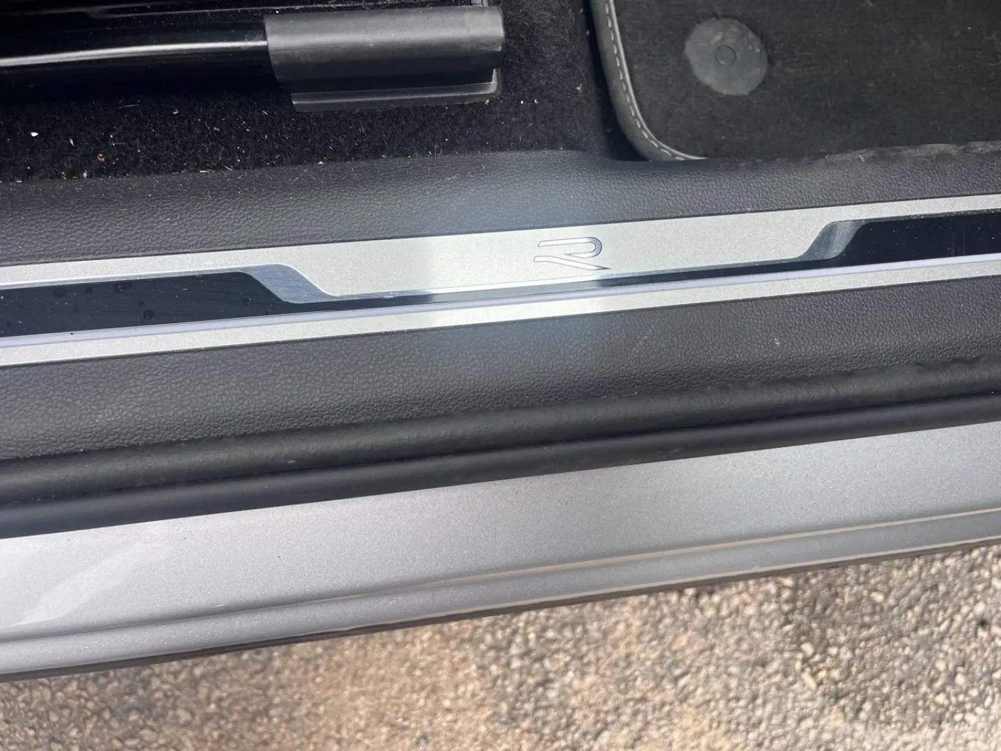 Gros plan sur la plaque de seuil de porte avec logo R du Volkswagen Tiguan gris dauphin métallisé.