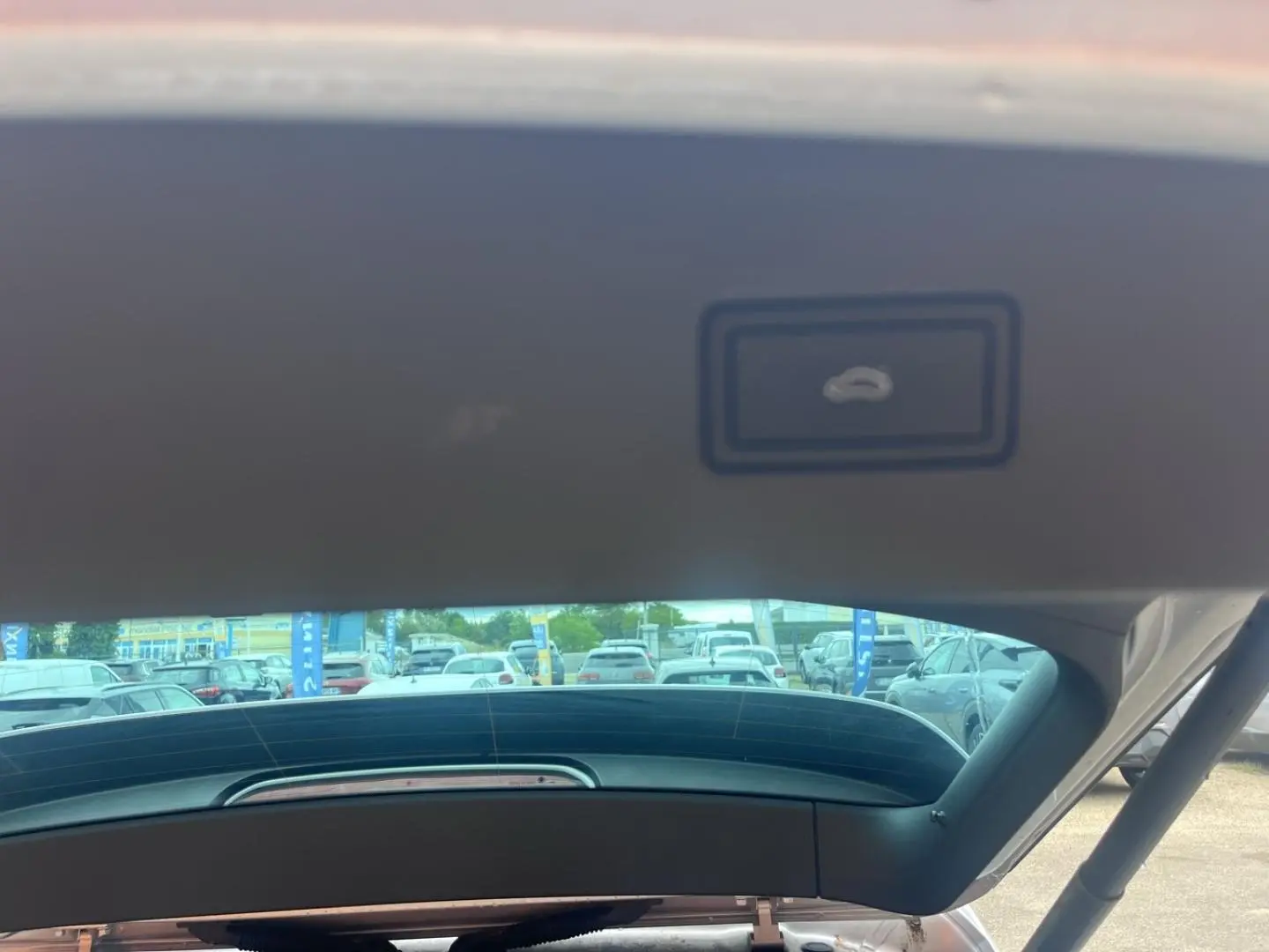 Vue intérieure du hayon ouvert du Volkswagen Tiguan gris dauphin métallisé, montrant la commande d'ouverture du coffre.