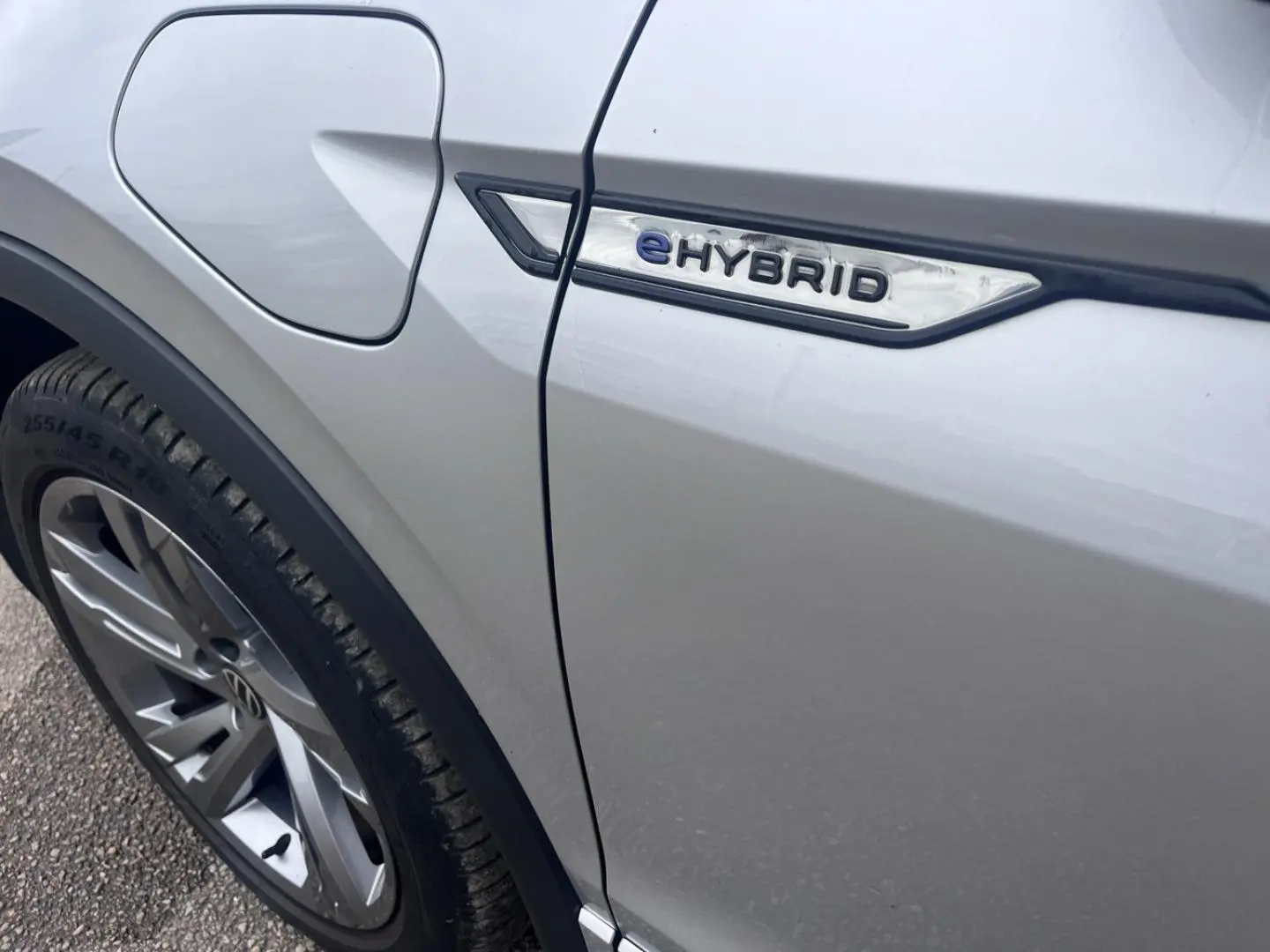 Gros plan sur le côté gauche gris dauphin métallisé du Volkswagen Tiguan 1.4 eHybrid avec logo eHybrid près de la trappe à carburant.