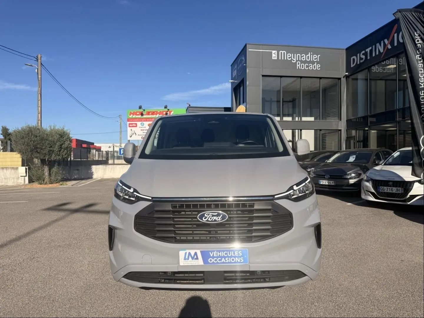 Vue frontale d'un Ford Transit Custom Fourgon gris 2024 avec calandre noire et plaque "Véhicules Occasions".