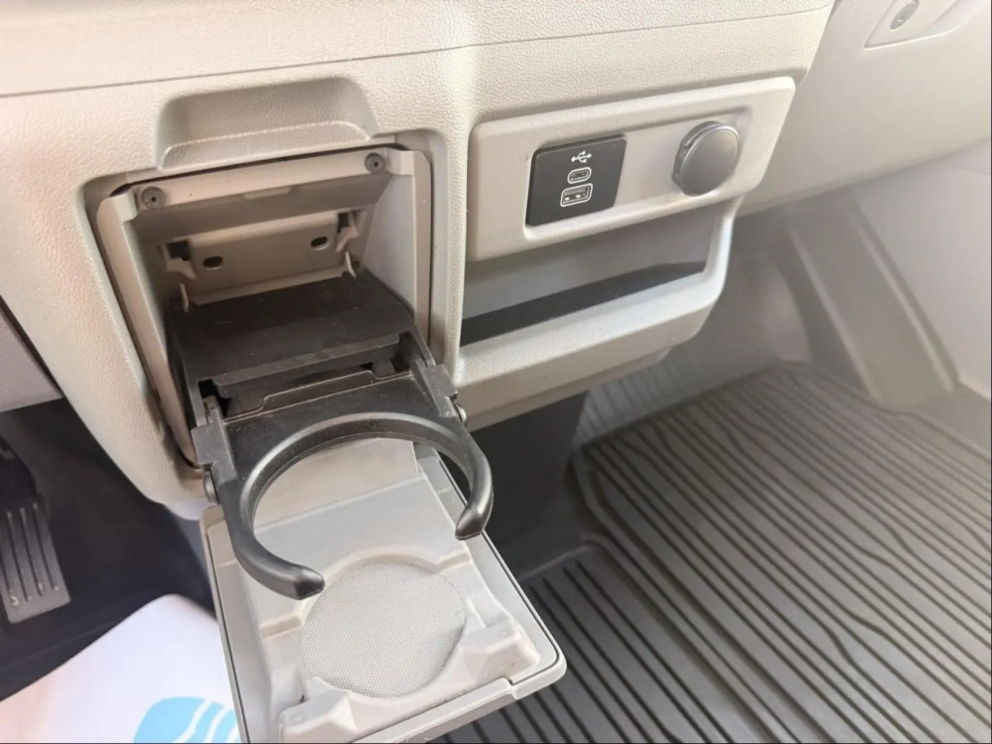 Détail intérieur du Ford Transit Custom 2024 montrant un porte-gobelet déplié et une prise USB sur fond gris.