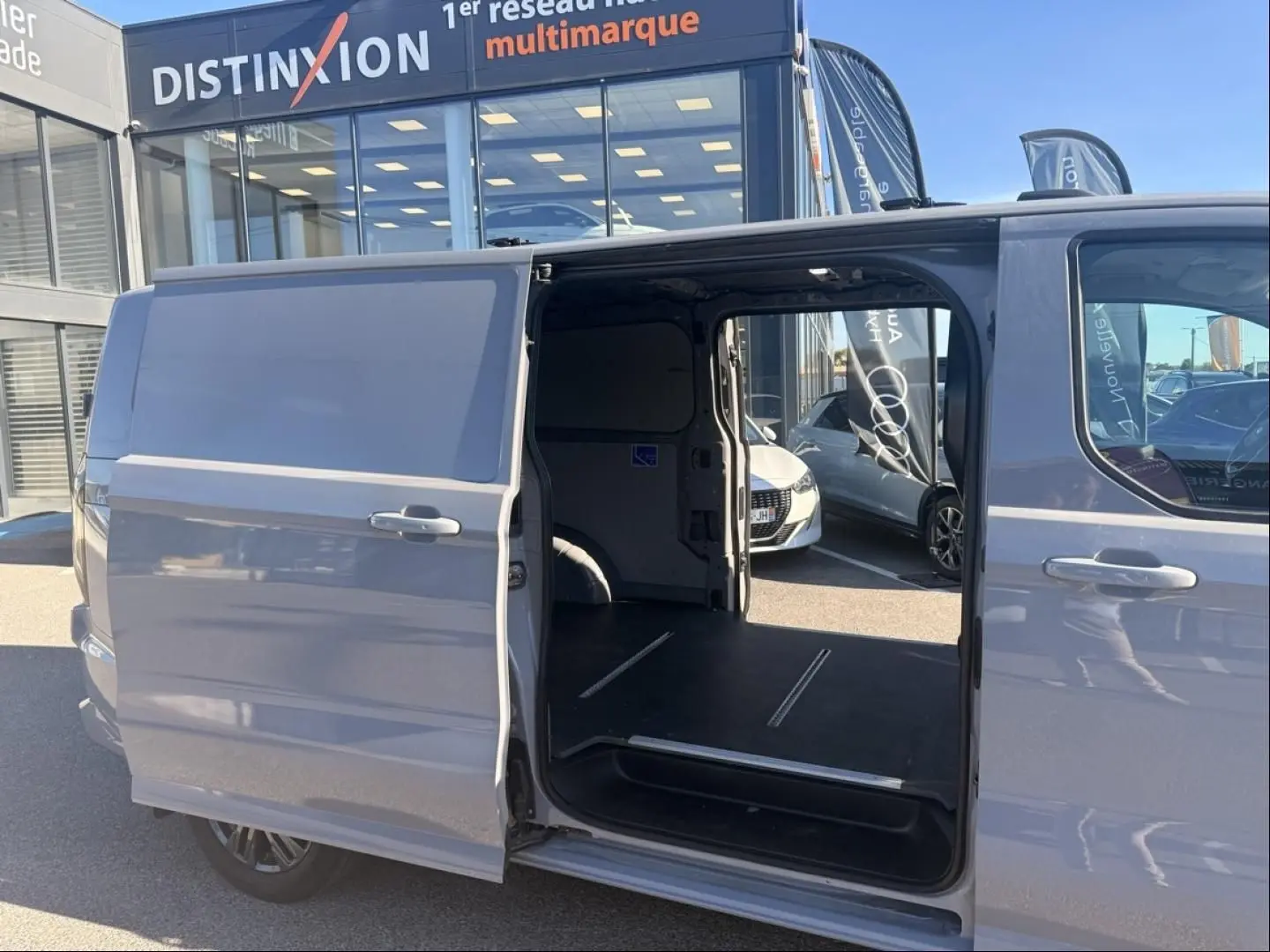 Vue latérale droite d’un Ford Transit Custom gris 2024 avec porte coulissante ouverte montrant l’espace de chargement vide.