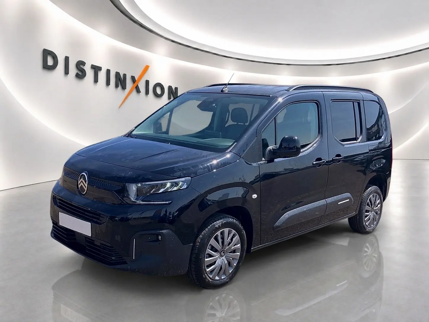 Citroën Berlingo noir vue 3/4 avant droit dans un showroom avec logo Distinxion en arrière-plan.