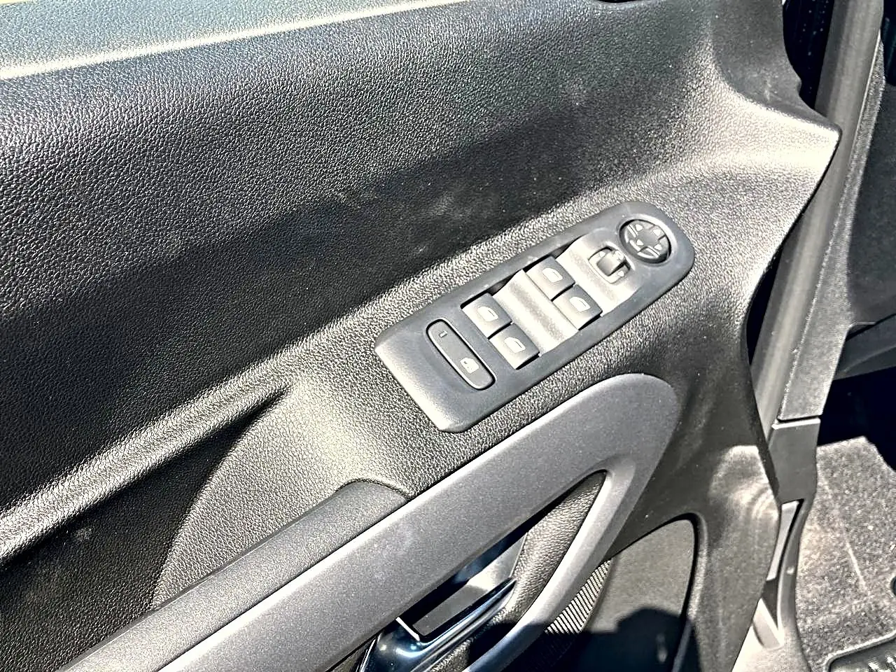 Gros plan sur la commande des vitres électriques côté conducteur du Citroën Berlingo noir, intérieur en plastique noir.