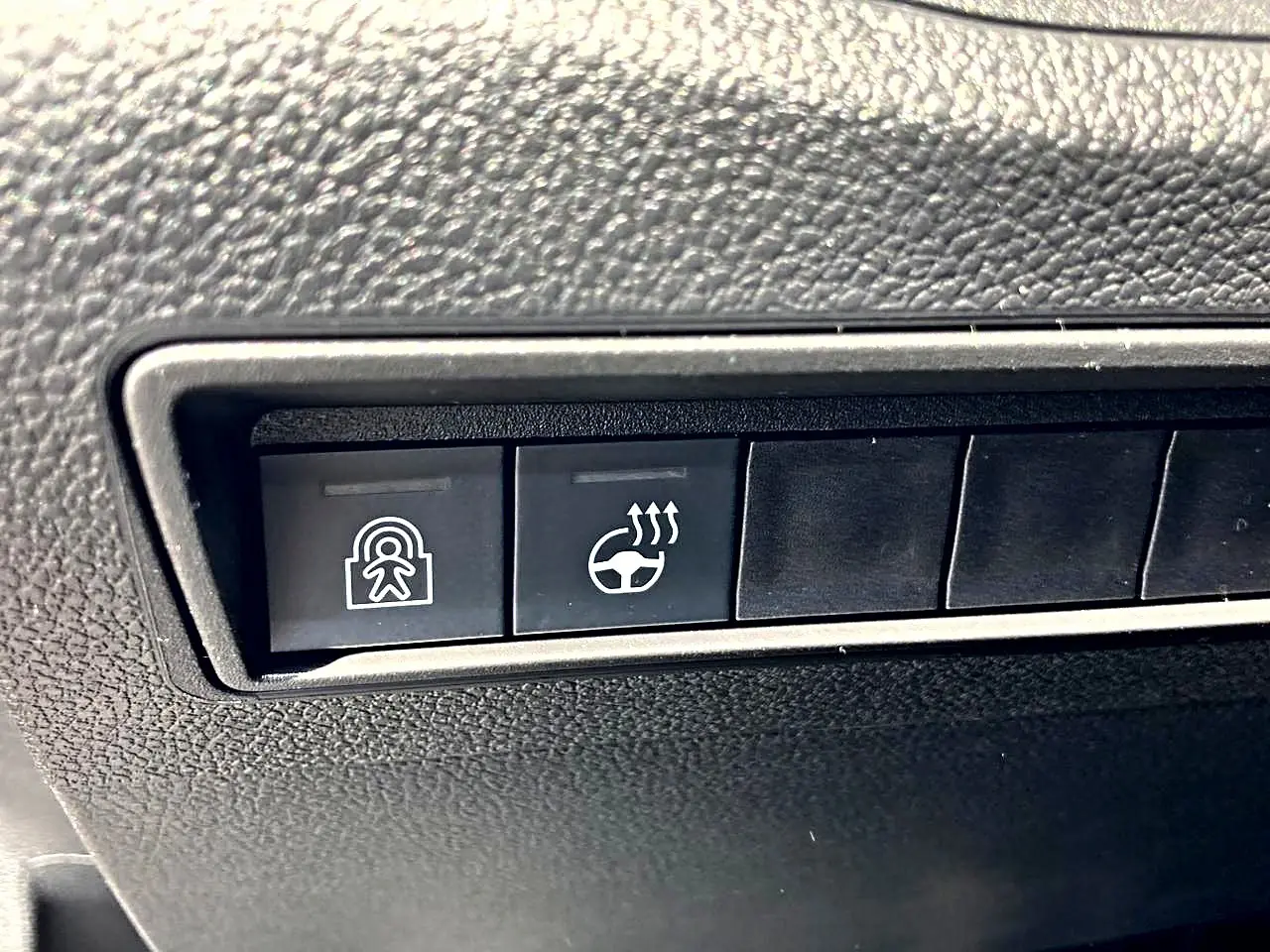 Gros plan sur les boutons de commande du tableau de bord noir du Citroën Berlingo N1 2026, dont le volant chauffant.