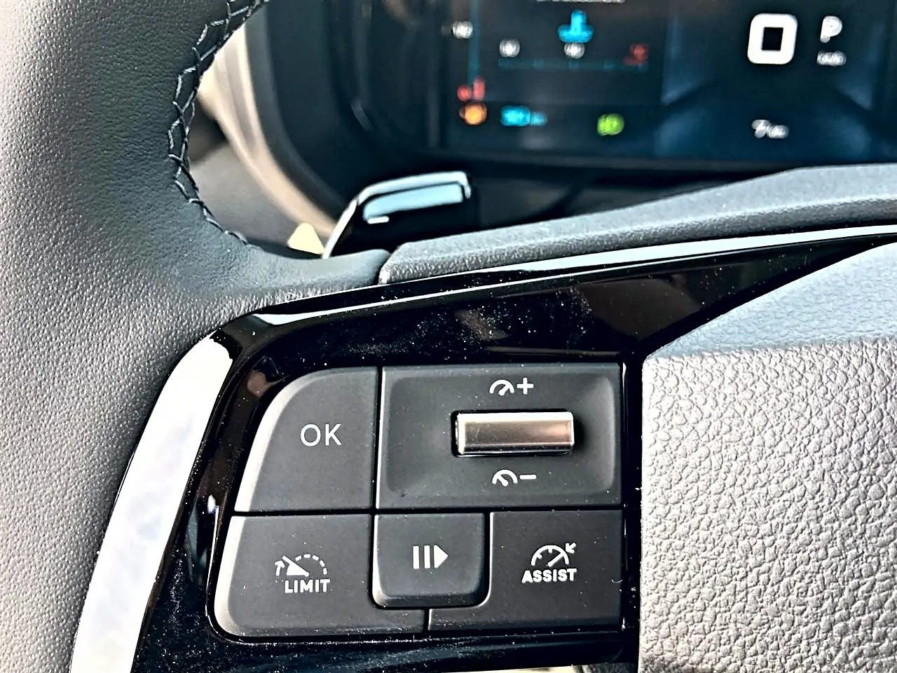 Gros plan sur les commandes noires du volant multifonction du Citroën Berlingo N1, avec écran de bord flou en arrière-plan.