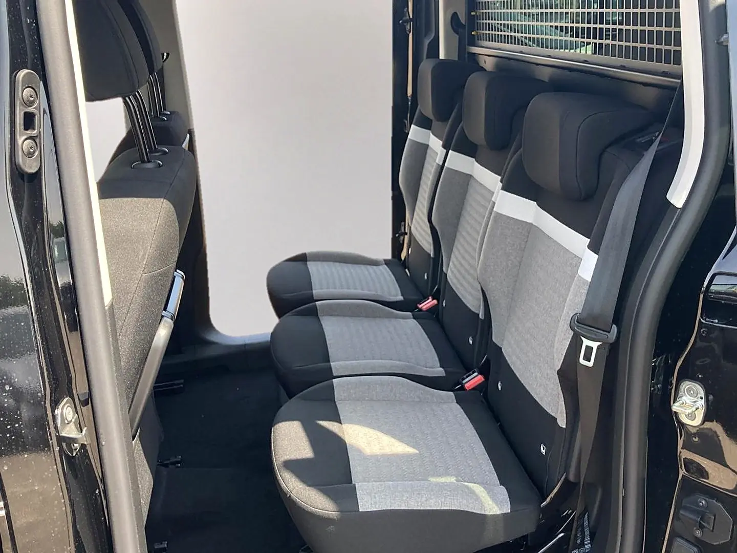Vue latérale droite des trois sièges individuels arrière gris et noir du Citroën Berlingo noir avec porte latérale ouverte.
