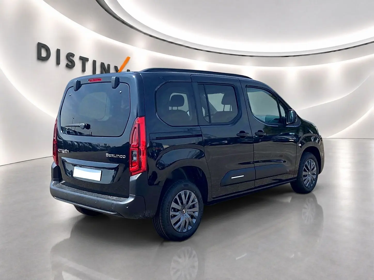 Vue 3/4 arrière droite d'un Citroën Berlingo noir avec portes latérales et jantes alu dans un showroom lumineux.