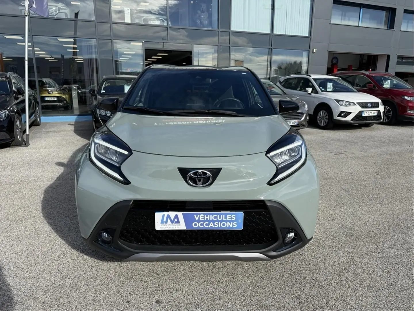 Vue avant frontale d'une Toyota Aygo X 2025 vert aventurine avec toit noir, mettant en valeur ses phares distinctifs et sa calandre noire.