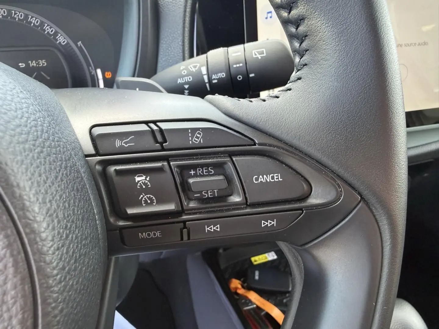 Gros plan sur les commandes au volant de la Toyota Aygo X 2025, montrant les boutons de régulateur et d'assistance.