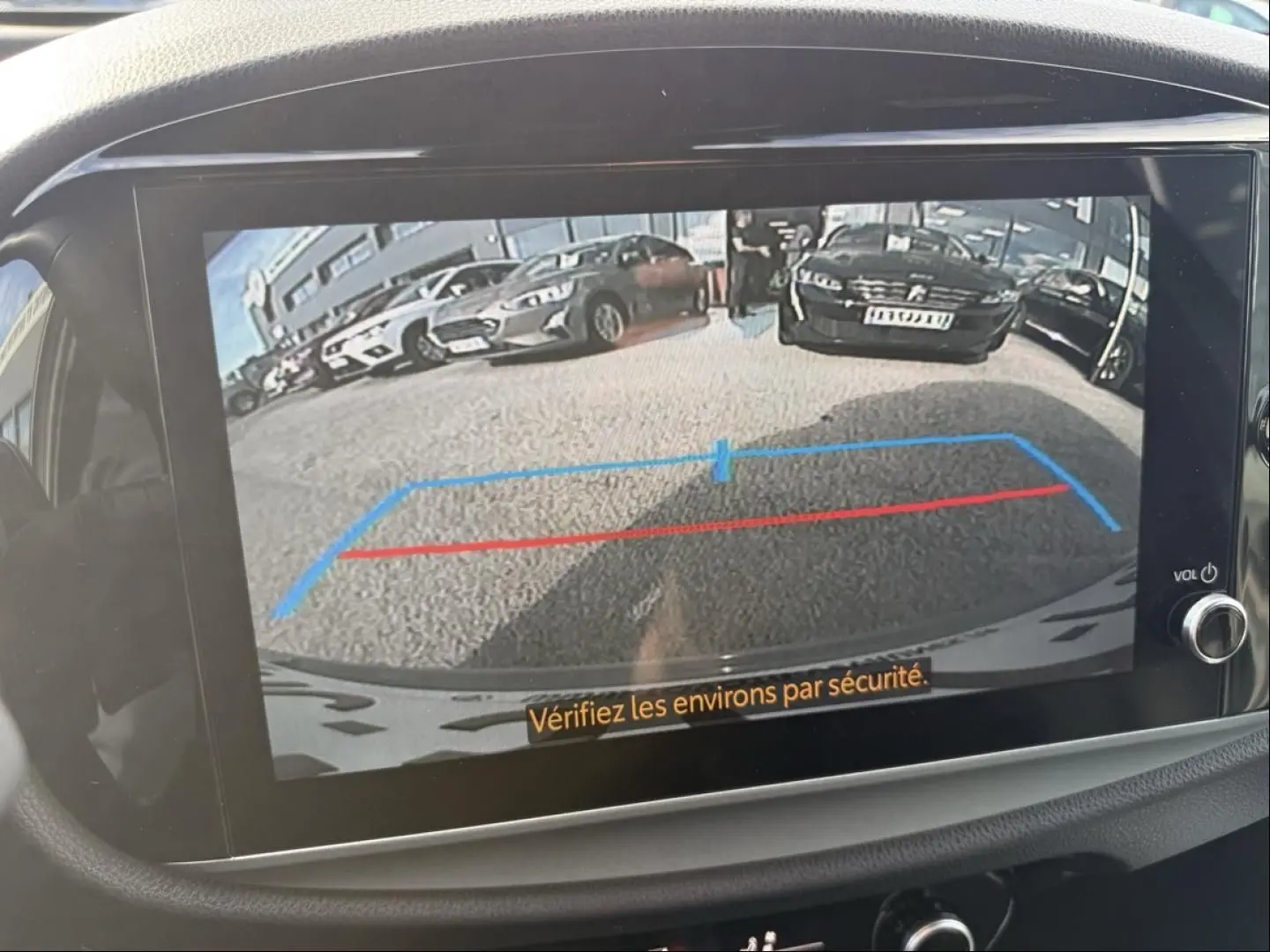 Vue de l'écran de caméra de recul d'une Toyota Aygo X 2025 vert aventurine avec toit noir, montrant les lignes d'aide au stationnement.
